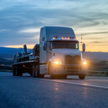 Freight Shipping from North Carolina to New York - Flatbed carriers white semi truckload at dusk