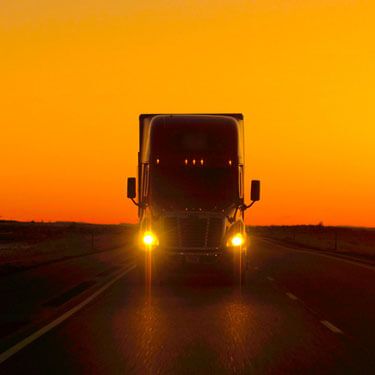 Shipping from South Carolina to Texas - Truck with headlights on against orange sky