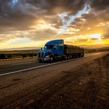 Freight Shipping from Oklahoma to Florida - Blue truck on highway with sun and clouds