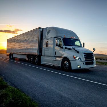 Freight Shipping from Washington DC to California - White truck on highway with sun off in horizon