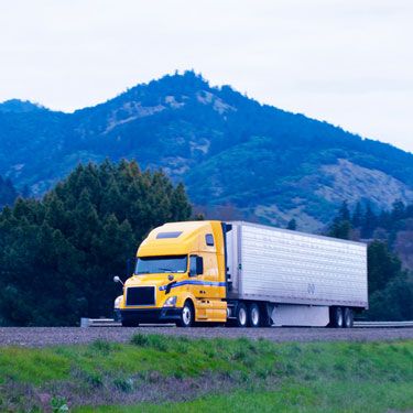 yellow cab semi-truck on Minnesota highway with mountains in background