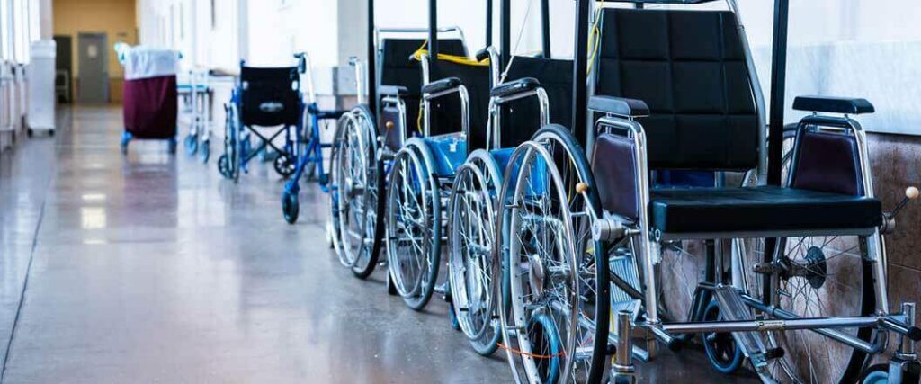 Multiple wheelchairs in a hospital that are lined up behind one another